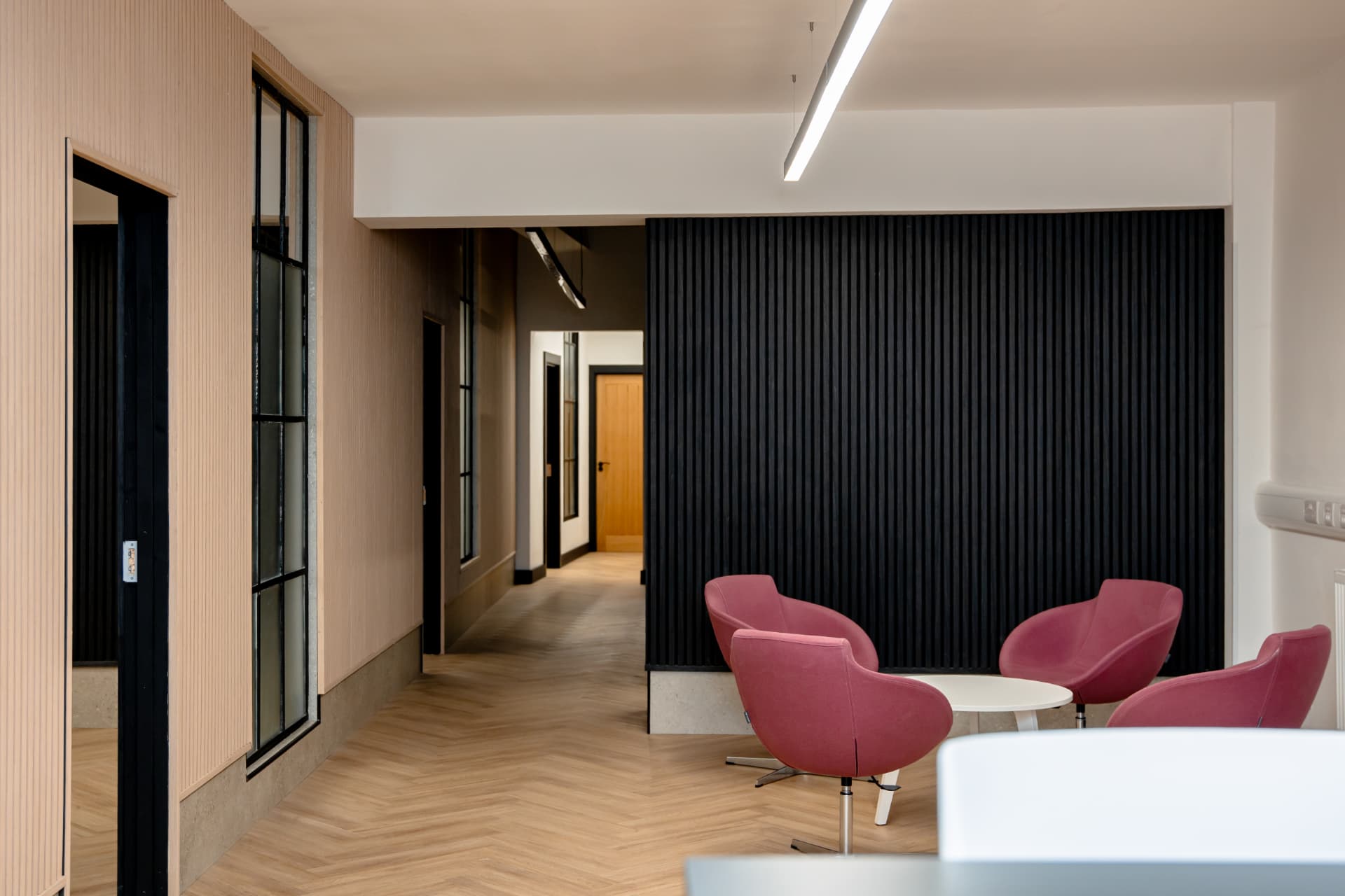 Breakout lounge at Patrick's with pink armchairs, coffee table and slatted feature wall
