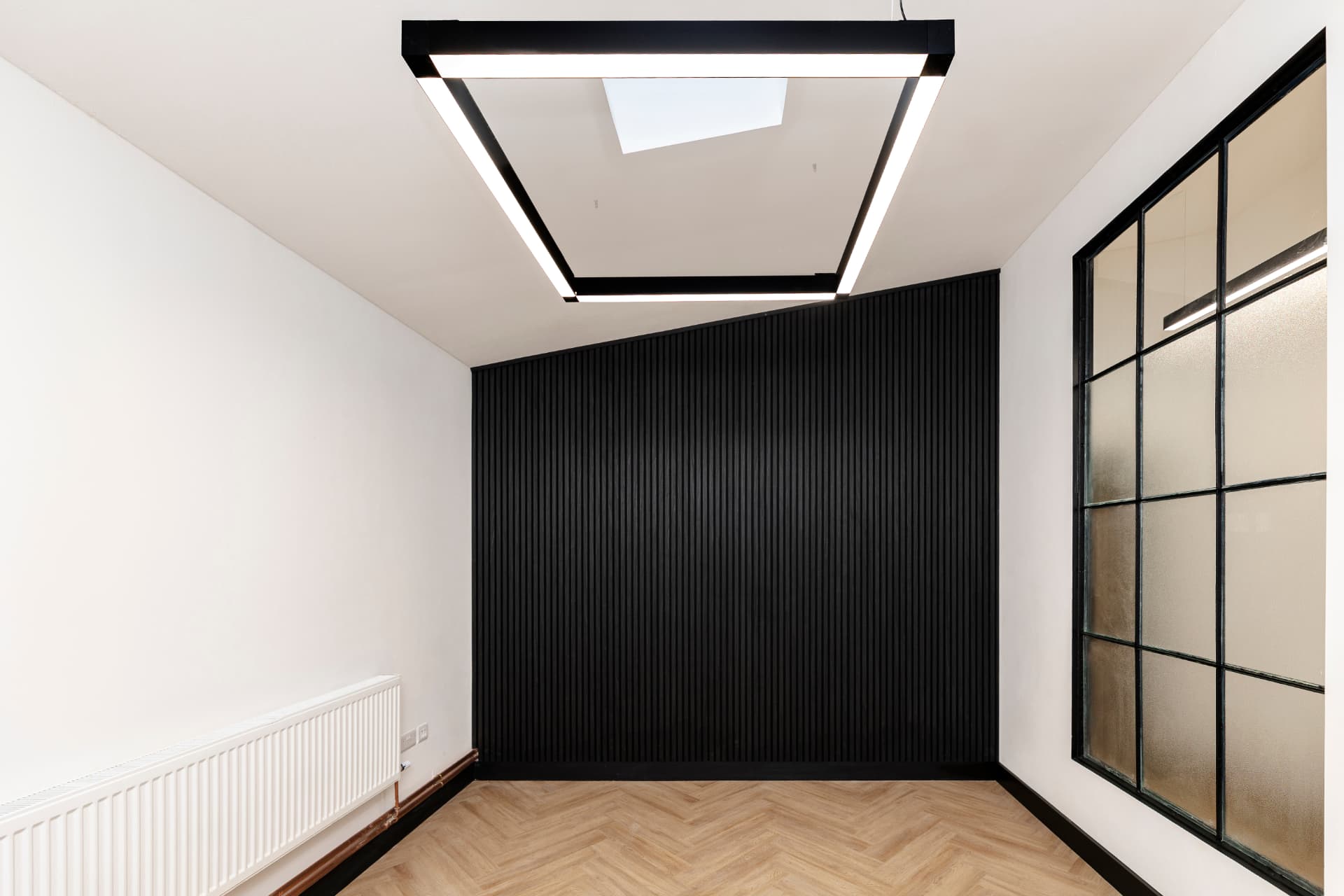 Small private room at Patrick's with black slatted feature wall, feature ceiling lighting and herringbone flooring