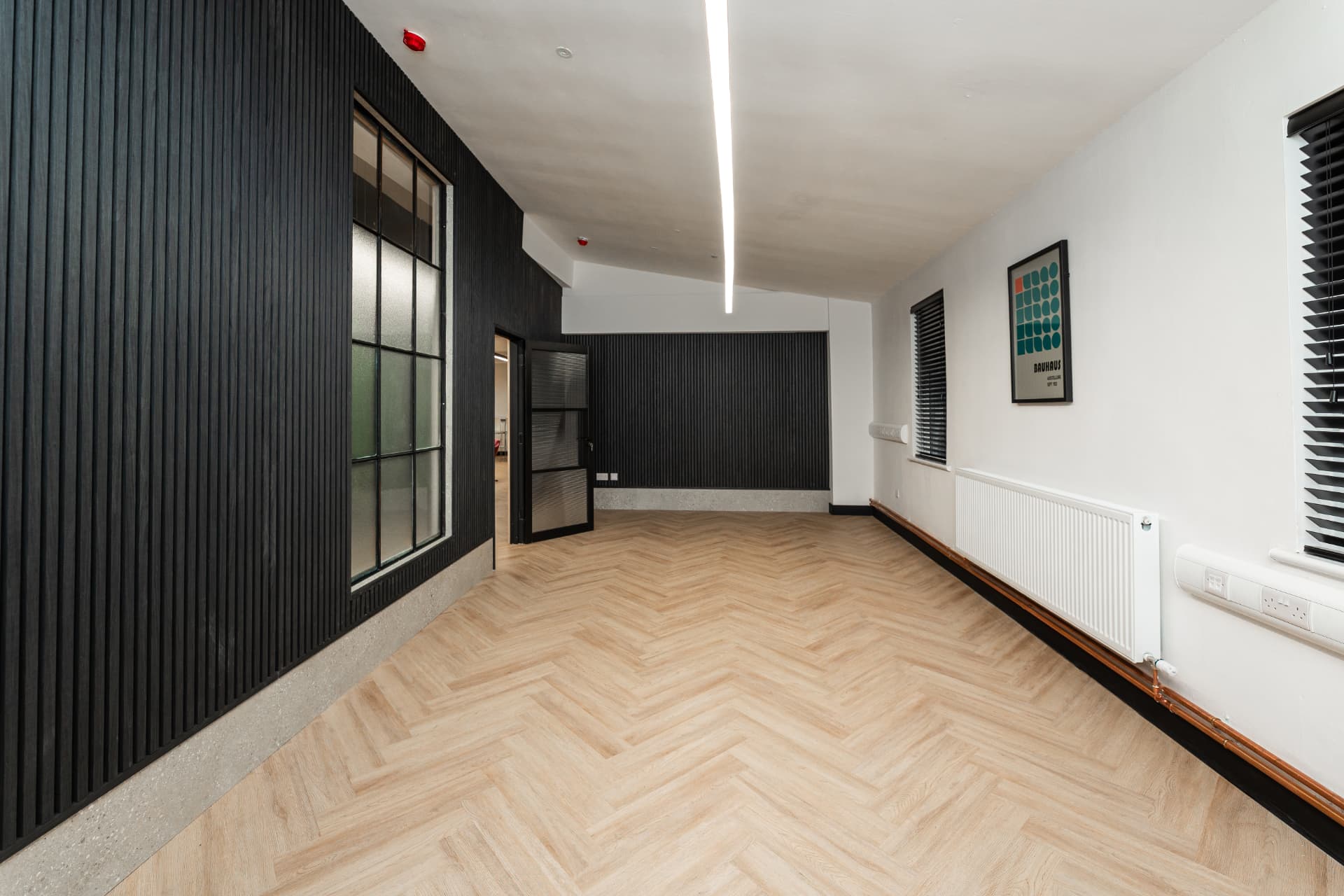 Large private room at Patrick's with black slatted walls, herringbone flooring and feature lighting
